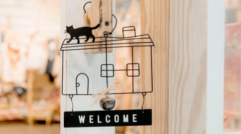 Welcome sign in the outline of a house with a cat on top