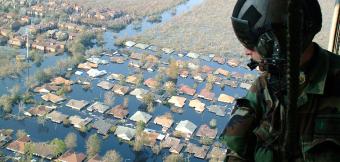 Soldier in helicopter overlooking flooded community