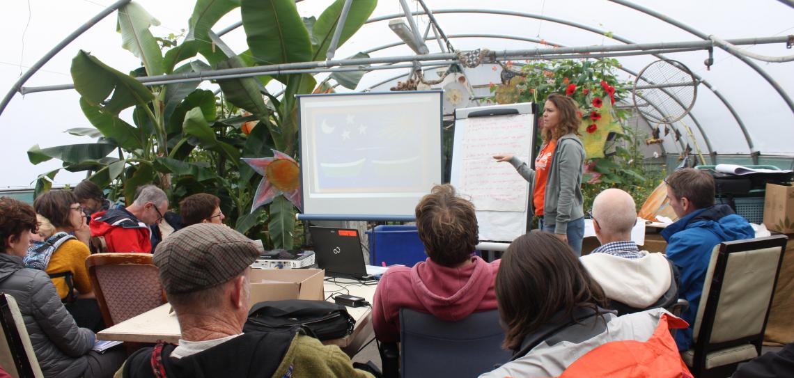 Students gather around a presentation with plants in the background