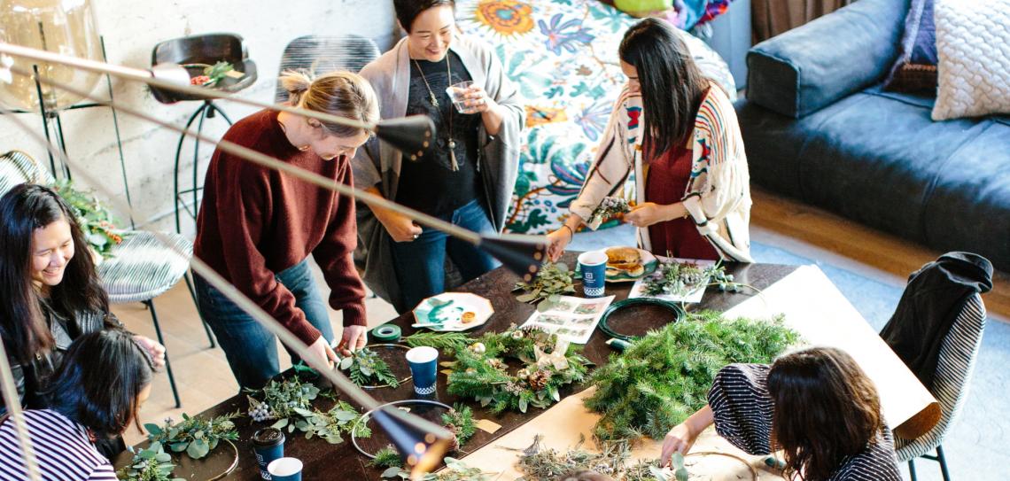 Six people are gathered around a table working on crafts