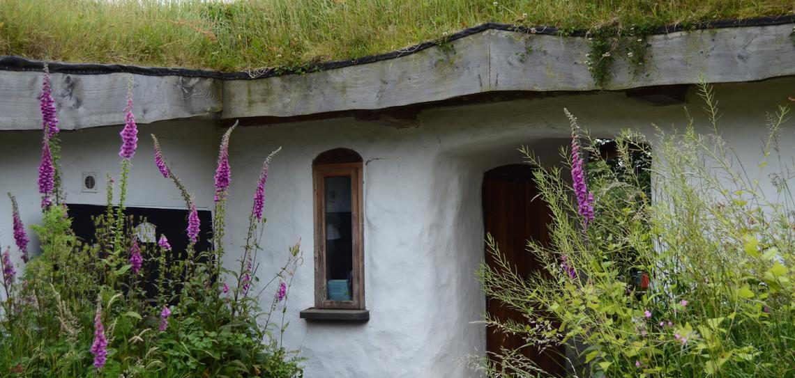 White house with a green roof and bushes in front