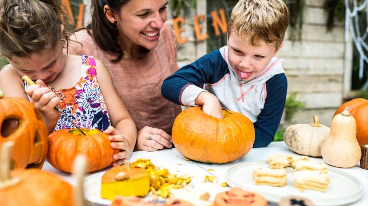 A woman and two children carve Halloween lanterns.