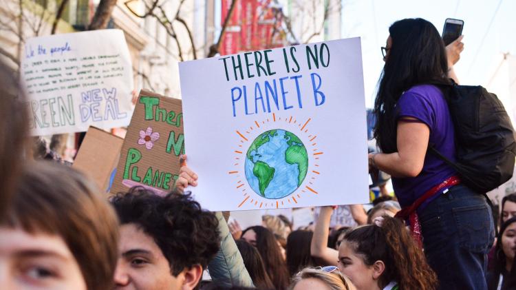 Young people protesting in the street with 'There is no Planet B' poster