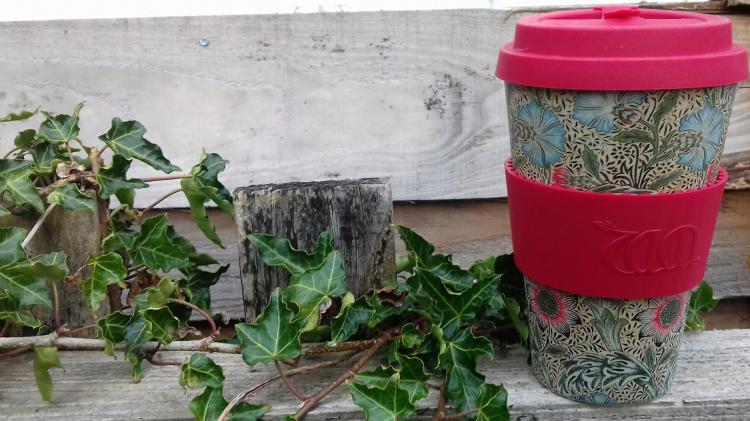 Reusable coffee cup on a wooden fence with ivy