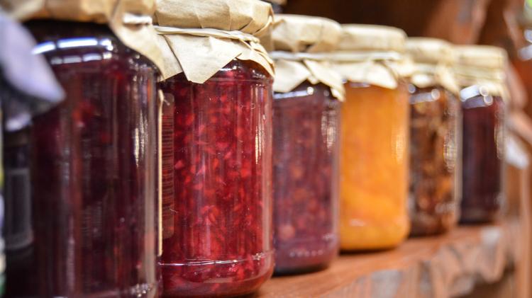 Jars of jam lined up on a shelf 