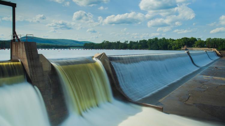 Hydropower Damn with water falling over edge against blue skies