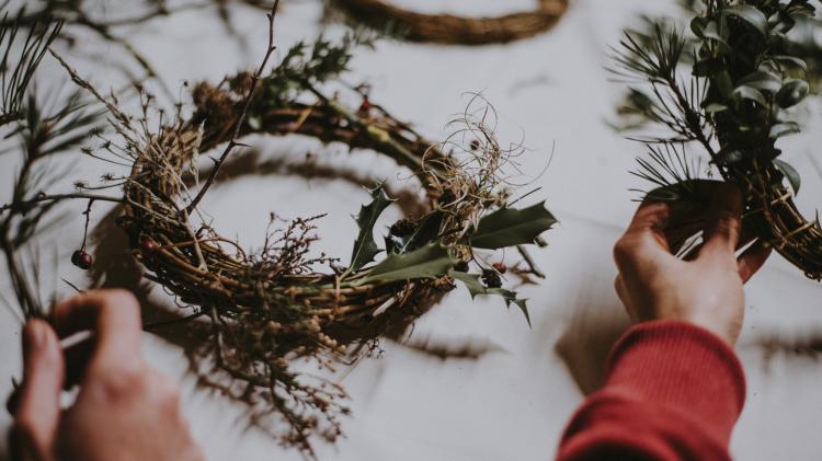 Two hands create festive wreaths out of branches