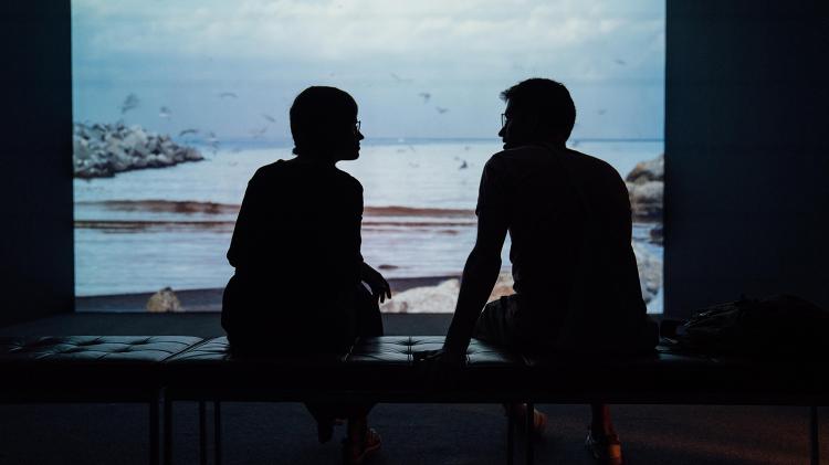 Silhouettes of two people talking in front of a picture of nature.